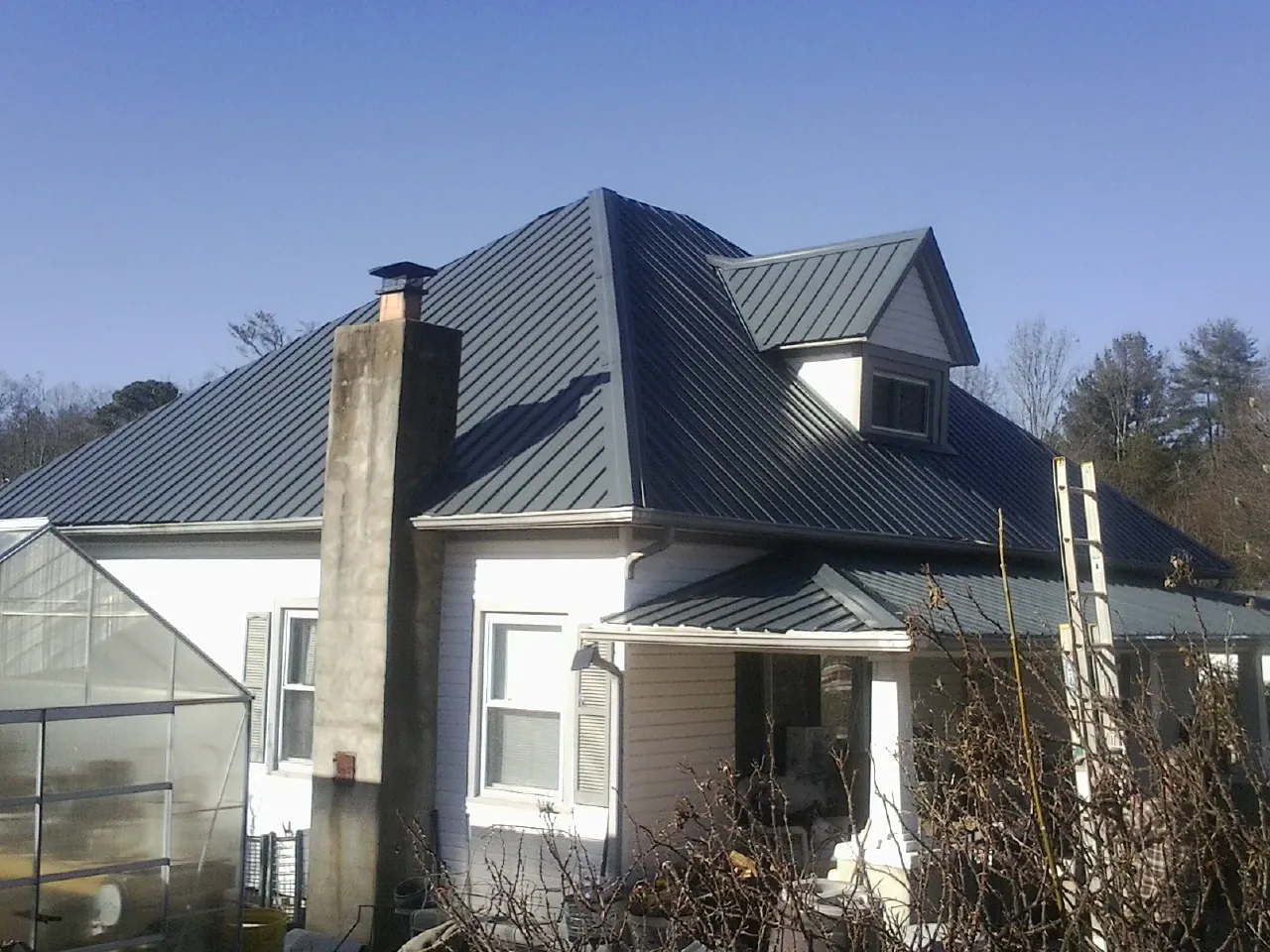 Dark blue standing seam metal roof on a white farmhouse with dormer — Slate & Tile Roof Repair by Roofing Brothers in Coffeen