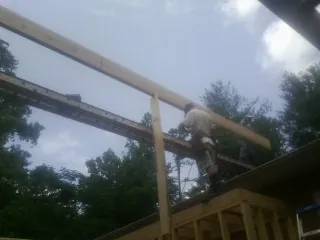 Carpenter setting a ridge beam over a new addition frame — Ice Dam Removal by Roofing Brothers in Coffeen