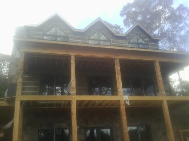 Dormers and porch framing on a large log home under construction — Roof Coating work by our crew in Coffeen