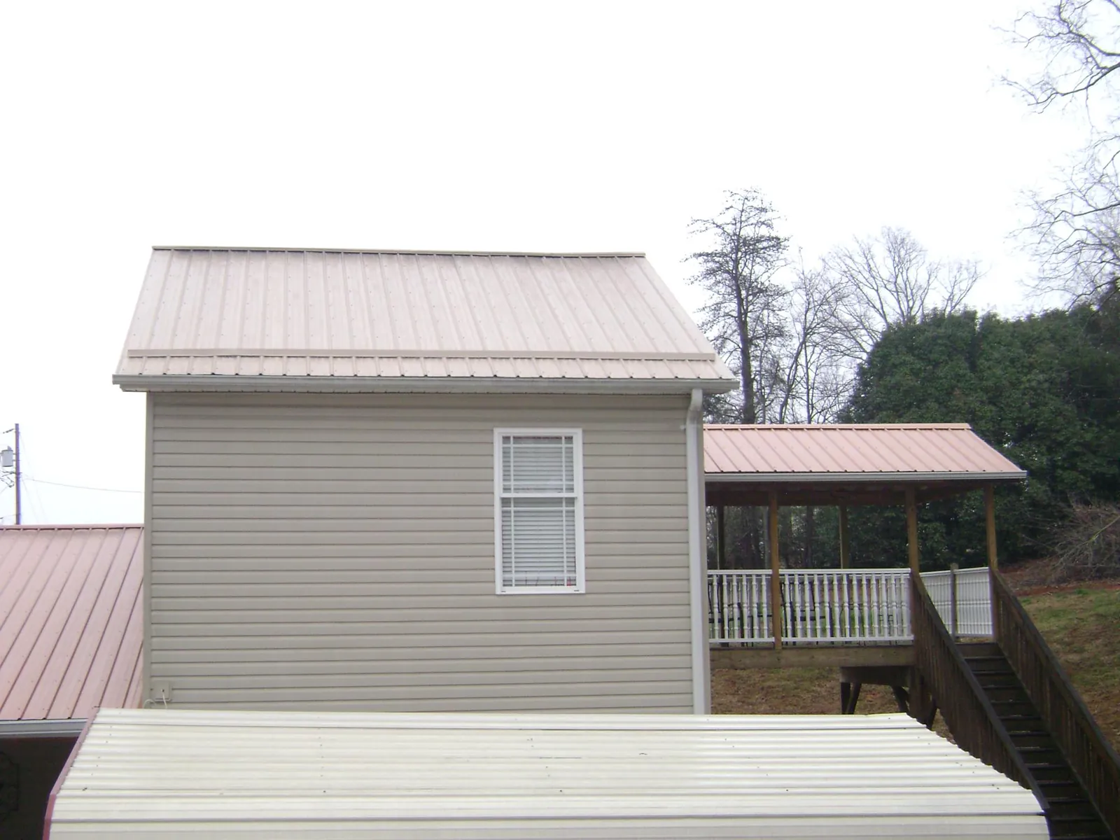 Tan metal roofs on a two story addition and attached porch, from a Roof Replacement job in Coffeen